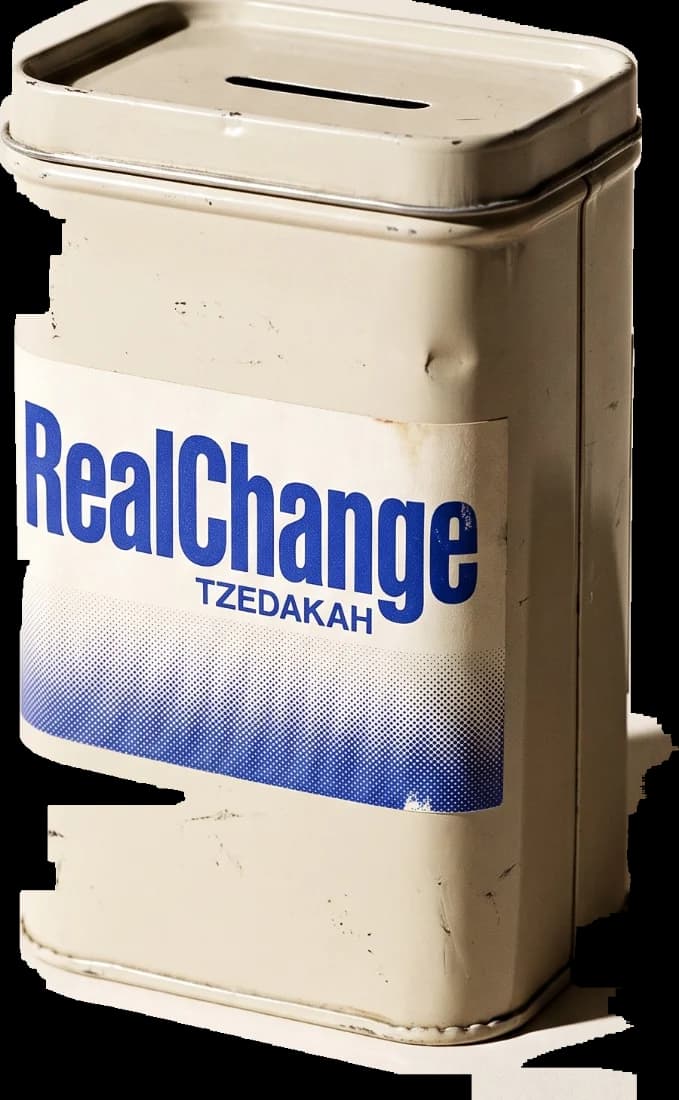 A vintage metal tzedakah tin printed RealChange TZEDAKAH, with a coin slot in its folded lid.